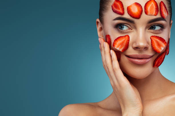 Happy young girl with facial mask of strawberry on her face